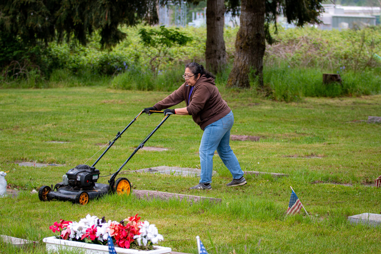 Marie Triana, whose family rests at the Greenwood Memorial Park, mows the grass along with other members of the work party to prepare for the rededication ceremony that will be held Memorial Day weekend.